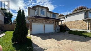Kitchener apartment for rent - A house with a garage and a tree in front of it.