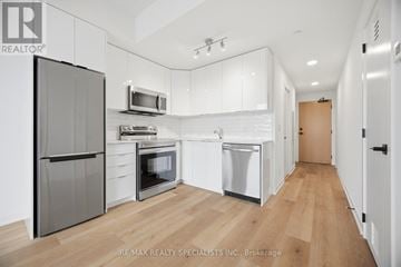 Brantford condo for rent - A kitchen with white cabinets and a wooden floor.