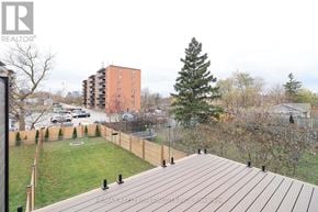 Mississauga (Lakeview) apartment for rent - A wooden deck overlooks a grassy area with a tree and apartment buildings in the background.