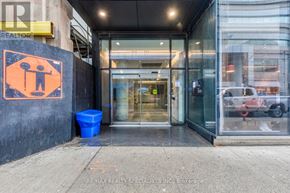 Toronto (Waterfront Communities) condo for rent - The entrance to a building with a glass door and a blue trash can in front.