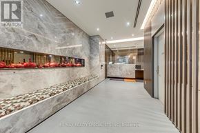 Toronto (Waterfront Communities) condo for rent - A hallway with a marble wall and a row of red chairs on the left side.