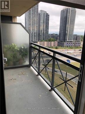 Toronto (Etobicoke West Mall) condo for rent - A balcony with a glass door and a metal railing overlooking a parking lot and buildings.