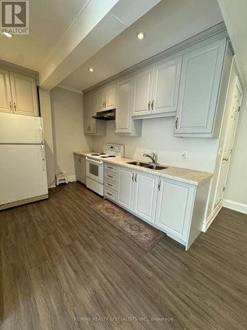 Shelburne multi-family for rent - A kitchen with white cabinets and a white fridge.