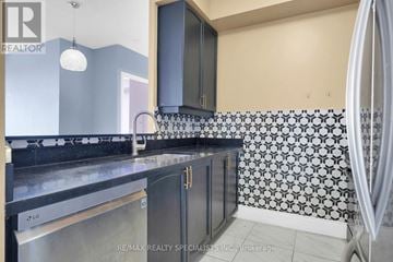 Toronto (West Humber-Clairville) condo for rent - A kitchen with a black countertop and a black and white tiled backsplash.