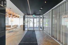 Oakville (Go Glenorchy) condo for rent - A hallway with a black carpet and wooden floors leading to a glass door.