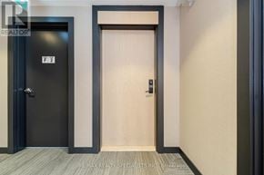 Oakville (Go Glenorchy) condo for rent - A hallway with a black door on the left and a wooden door on the right.