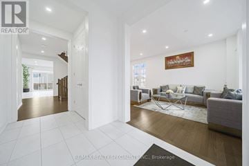 Adjala-Tosorontio (Colgan) apartment for rent - A spacious living room with a grey sofa and a wooden floor.