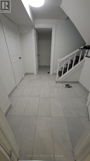 Oshawa (Vanier) apartment for rent - A hallway with a white tile floor and a staircase.
