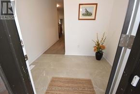 Thorold (Rolling Meadows) townhouse for rent - A hallway with a rug and a vase with flowers on the floor.