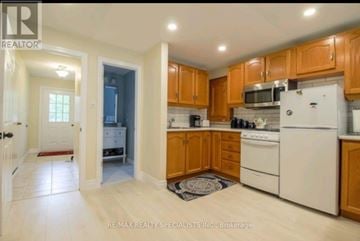 Orangeville apartment for rent - A kitchen with white appliances and wooden cabinets.