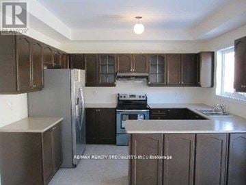 Brampton (Bram East) apartment for rent - A kitchen with brown cabinets and a black stove top oven.