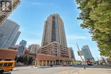 Mississauga (City Centre) condo for rent - A tall building stands in the middle of a city street.