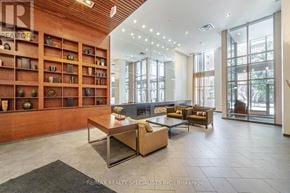 Mississauga (City Centre) condo for rent - A living room with a couch, coffee table, and a shelf with various objects.