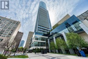 Toronto (Bay Street Corridor) condo for rent - A tall glass building stands in front of other buildings on a sunny day.