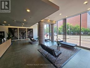 Toronto (Waterfront Communities) condo for rent - A waiting area with a black couch and a table with a vase of flowers on it.