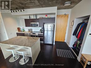 Toronto (Waterfront Communities) condo for rent - A kitchen with a granite countertop and bar stools.