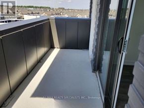 Oakville (Jm Joshua Meadows) condo for rent - A balcony with a glass door and a view of buildings in the distance.