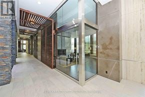 Mississauga (City Centre) condo for rent - A hallway with a stone wall and a glass door.
