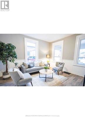 Brantford apartment for rent - A living room with a grey sofa, a grey armchair, a coffee table, and a green plant.