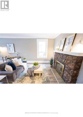 Brantford apartment for rent - A living room with a grey couch and a stone wall.