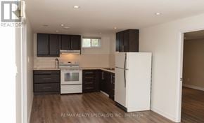 St. Catharines (Bunting/Linwell) duplex for rent - A kitchen with white appliances and dark wood cabinets.