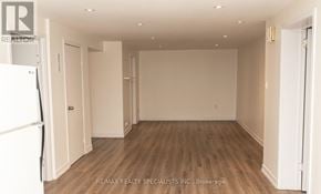 St. Catharines (Bunting/Linwell) duplex for rent - A spacious room with wooden flooring and white walls, with a door on the left and a partially visible door on the right.