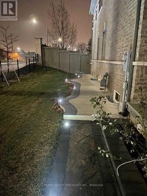 Brampton (Credit Valley) apartment for rent - A nighttime view of a residential area with a well-lit pathway and a building on the right.