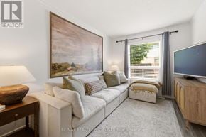 Hamilton (Stoney Creek Mountain) townhouse for rent - A living room with a white couch, a wooden side table, a painting on the wall, and a flat screen TV.