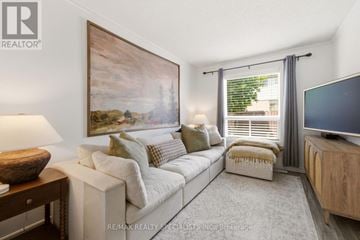 Hamilton (Stoney Creek Mountain) townhouse for rent - A living room with a white couch, a wooden side table, a painting on the wall, and a flat screen TV.