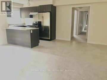 Brampton (Northwest Brampton) townhouse for rent - A kitchen with a refrigerator, sink, and countertop is shown in a real estate listing.