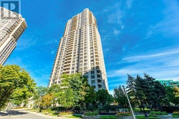Mississauga (Hurontario) condo for rent - A tall building with a sign that reads "AMAKAREALTY SPECIALISTS INC. Brokerage" in front of it.