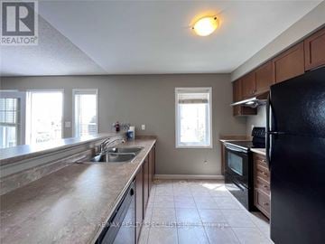 Milton (Ha Harrison) townhouse for rent - A kitchen with a black refrigerator, a sink with a faucet, and a window.