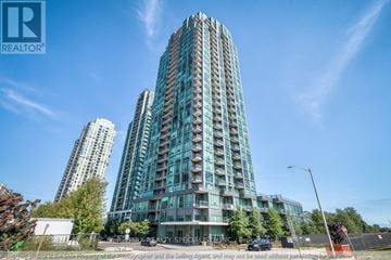 Mississauga (City Centre) condo for rent - A tall residential building with a glass facade stands prominently in the foreground.