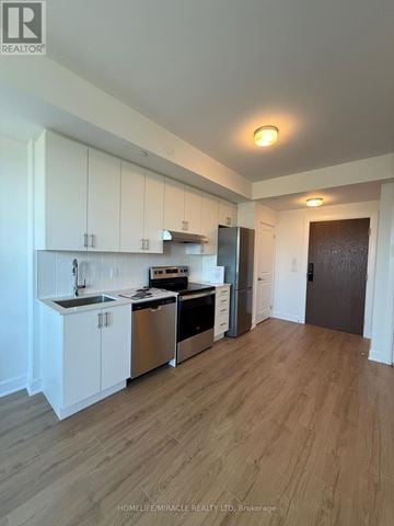 Oakville (Jm Joshua Meadows) condo for rent - A kitchen with white cabinets and a wooden floor.