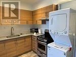 Toronto (Trinity-Bellwoods) apartment for rent - A kitchen with wooden cabinets and a white fridge.