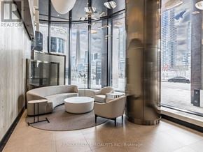 Toronto (Waterfront Communities) condo for rent - A modern living room with a view of the cityscape outside the large windows.