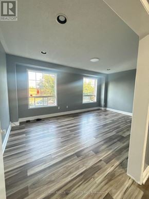 Brampton (Fletcher's Creek Village) townhouse for rent - A room with wooden flooring and a window showing a view of a building.