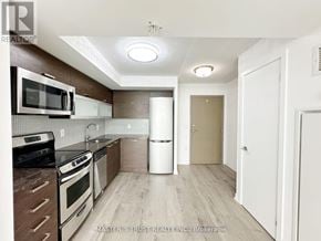 Toronto (Little Portugal) condo for rent - A kitchen with a white fridge, black oven, and wooden cabinets.
