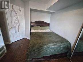 Toronto (Willowdale East) condo for rent - A bedroom with a bed, a coat rack, and a wooden floor.