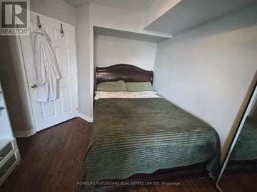 Toronto (Willowdale East) condo for rent - A bedroom with a bed, a coat rack, and a wooden floor.