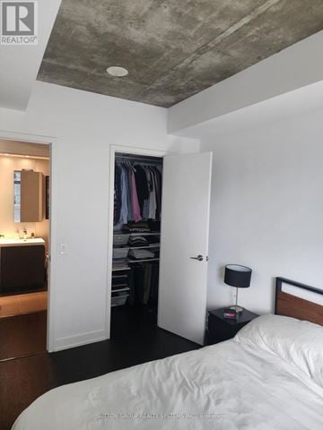 Toronto (Niagara) condo for rent - A bedroom with a bed, a nightstand with a lamp, and a closet with clothes.
