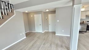 Barrie (Georgian Drive) condo for rent - A spacious room with wooden flooring and white walls.