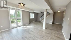 Barrie (Georgian Drive) condo for rent - A spacious room with a staircase and a large window.