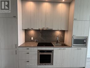 Toronto (Dovercourt-Wallace Emerson-Junction) condo for rent - A modern kitchen with white cabinets and a black countertop.