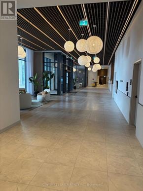 Brampton (Bram East) condo for rent - A hallway with a tiled floor and ceiling with lights hanging from it.