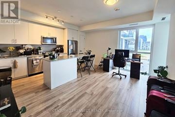 Oakville (Jm Joshua Meadows) condo for rent - A kitchen with a white island and a dining table with chairs.