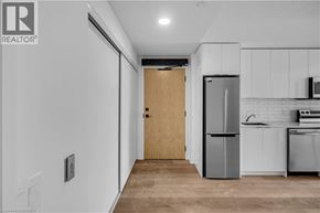 Brantford condo for rent - A kitchen with white cabinets and a wooden door.