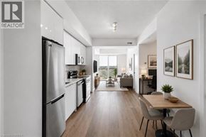 Brantford condo for rent - A modern kitchen with a refrigerator, dining table, and chairs.