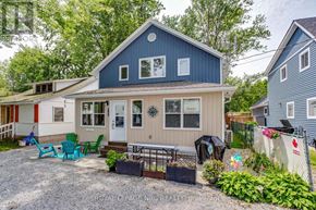 Fort Erie (Crystal Beach) duplex for rent - A blue house with a white door and windows is surrounded by a gravel driveway and a garden.