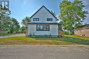 Fort Erie (Lakeshore) duplex for rent - A white house with a black roof is surrounded by greenery.